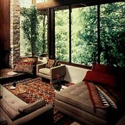 room with glass walls and wood beams and rustic pattern rug and pillows