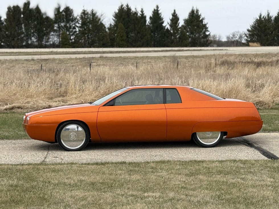 side profile of an orange 1999 cadillac eldorado concept car, emphasizing its streamlined body and large chrome wheels.