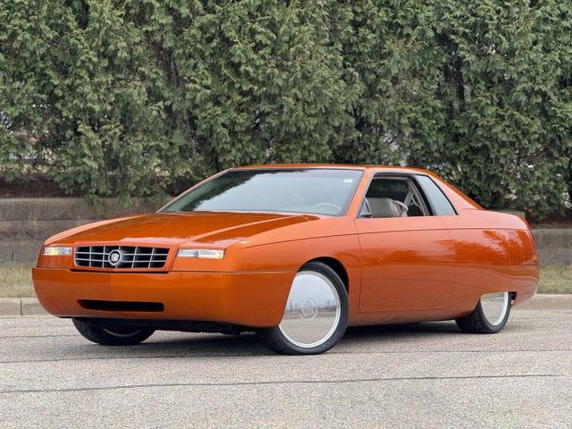front three quarter view of an orange 1999 cadillac eldorado concept car, showing its aerodynamic design and distinctive grille.