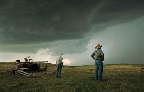 In de Sand Hills van Ogallala Nebraska pauzeren een stel boeren tijdens hun werk terwijl ze de dreigende en groeiende stormwolken in de verte in de gaten houden 2013