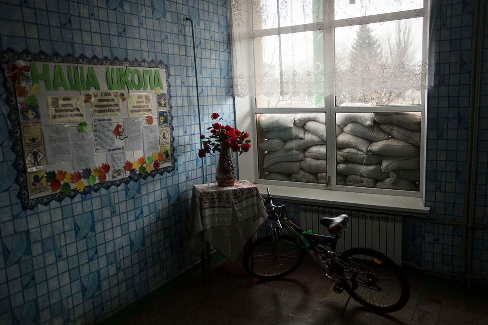 In Verchnjotoretske in de oblast Donetsk is een raam van een school afgedekt met zandzakken ter bescherming tegen mortierinslagen