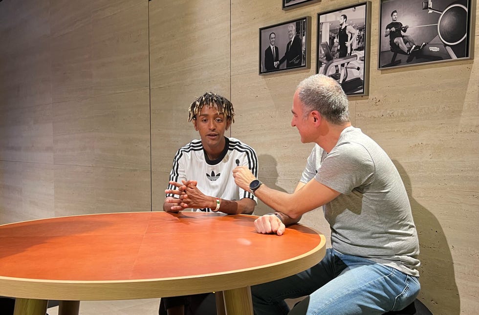 a man sitting at a table talking to another man