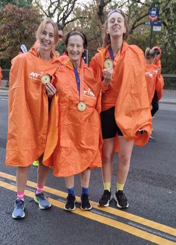 participants celebrating after a race wearing orange ponchos and displaying medals