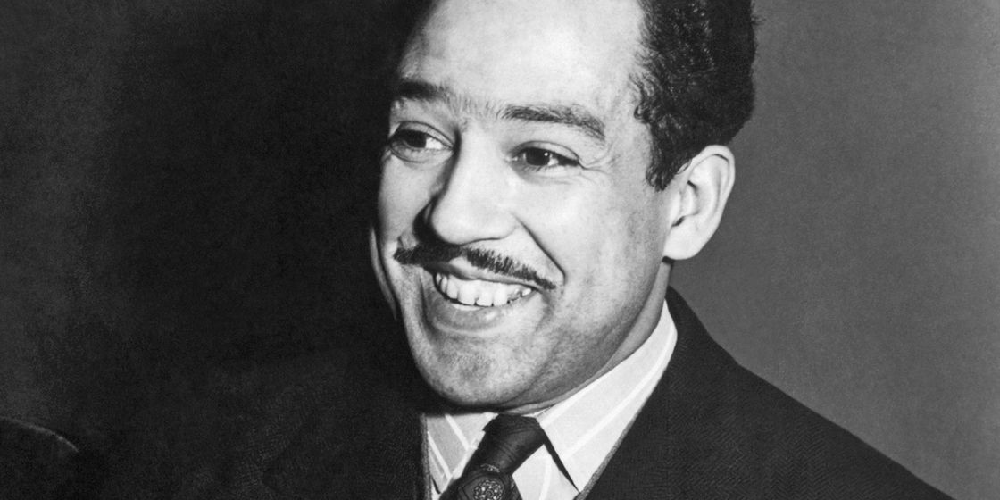black and white photo of langston hughes smiling past the foreground