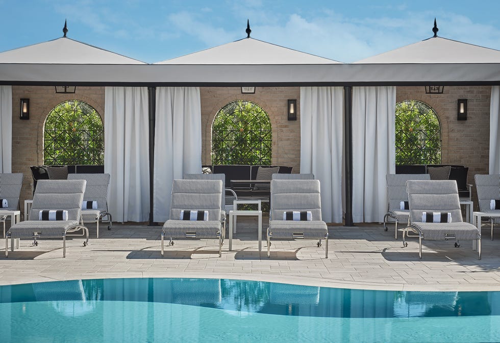 Lounge area with striped chairs, a table, and potted plants beside a pool.