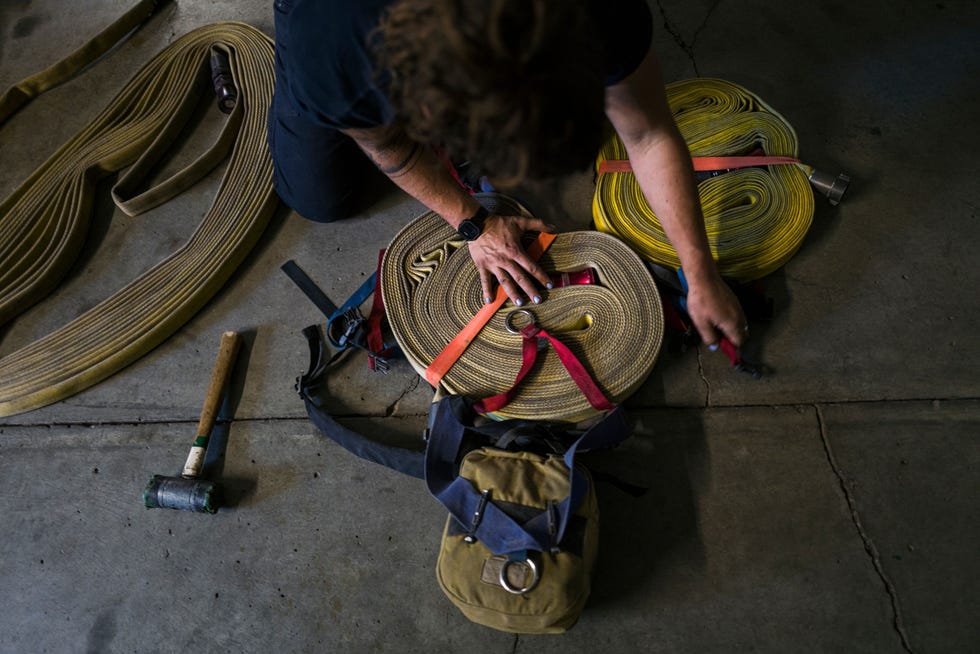 Madalyn Schiffel 26 uit Mountain Ranch Californi rolt een brandslang op na het nablussen van een brand die op 4 september 2021 de hele nacht nabij West Point Station in Californi heeft gewoed Schiffel zat een jaar lang als vrijwilligster bij de brandweer waarna ze in april bij CAL FIRE begon Daarvr werkte ze als profvoetbalster in Noorwegen en Seattle nadat ze direct na haar afstuderen was gescout Volgens Schiffel werken er maar heel weinig vrouwen bij de brandweer maar de meiden die ik daar heb leren kennen hebben veel succes en zijn enorm cool Ik heb gewoon bewondering voor die vrouwen  zowel die van mijn niveau als seizoenskracht als de vrouwelijke brandmeesters en commandeurs die ik ken