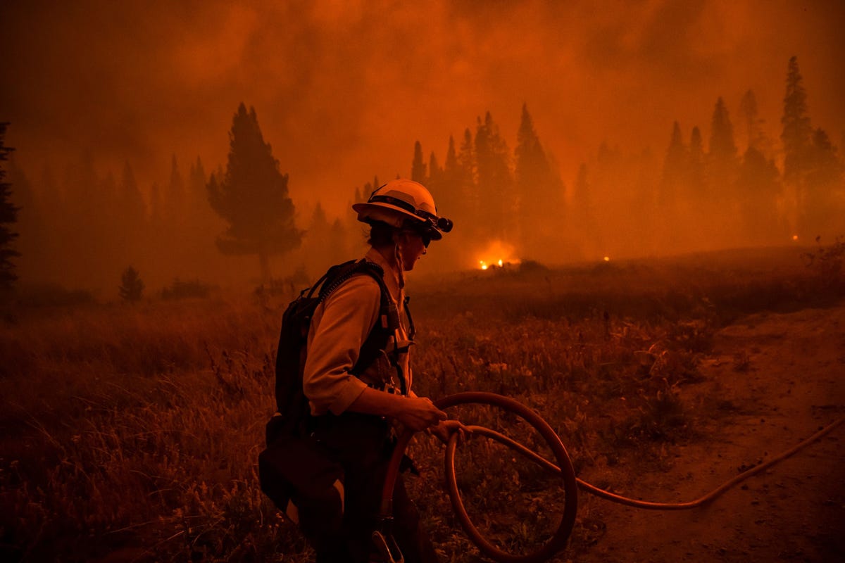 Bij een blokhut aan de Highway 50 in de buurt van Lake Tahoe in Californi zorgt Stephanie Lockhart 28 van het North Lake Tahoe Fire District ervoor dat woningen en schuilplaatsen worden behoed voor het grote Caldor Fire dat in een canyon in de buurt van de Sierra Nevadabergketen woedt 29 augustus 2021 De reusachtige bosbrand breidde zich uit op een dag waarop er vanwege de hoge kans op natuurbranden code rood was afgekondigd De luchtvochtigheid was laag de wind wakkerde aan en er was sprake van andere factoren die ervoor kunnen zorgen dat natuurbranden genoeg brandstof vinden om zich uit te breiden Volgens de autoriteiten brak het Caldor Fire op 14 augustus 2021 uit Op 19 oktober was de brand voor 98 procent onder controle maar inmiddels was zon negenhonderd vierkante kilometer bosgebied in vlammen opgegaan