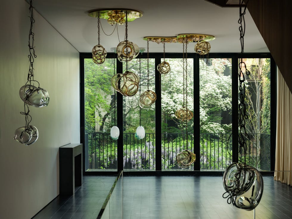 Modern interior featuring artistic light fixtures and large windows showcasing greenery.