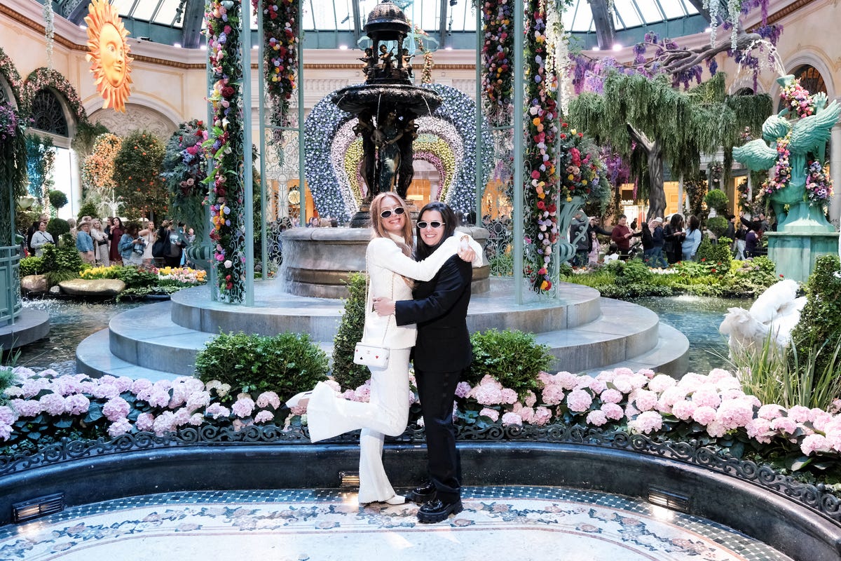 a bride in a white suit and a bride in a black suit pose at the bellagio in las vegas