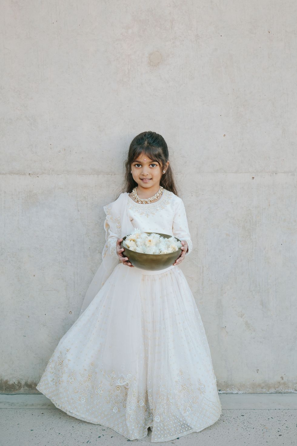 a person in a white dress holding a cake