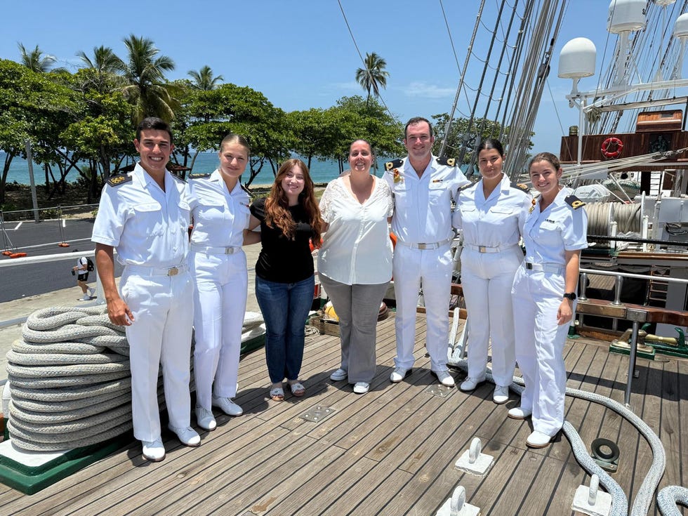 group of people posing on a ship deck with tropical background