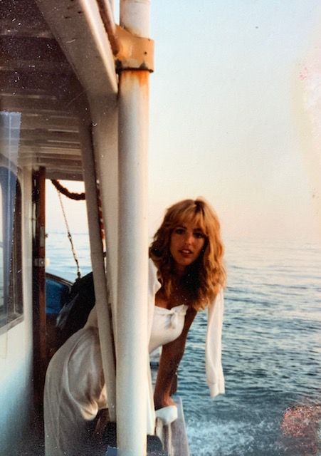 maureen dumont kelly leans off a boat in an all white outfit