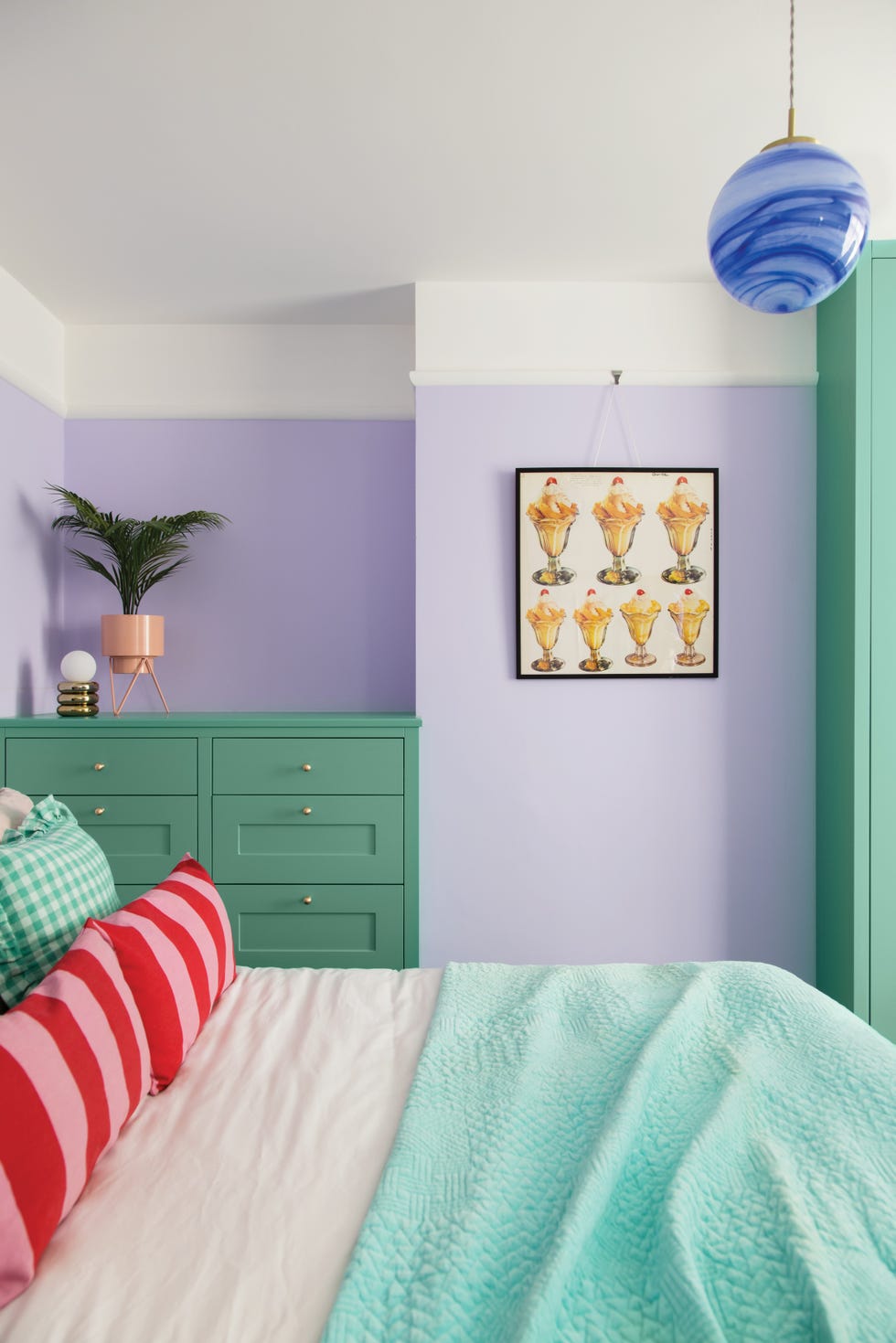 a lilac bedroom with green cabinetry and bed