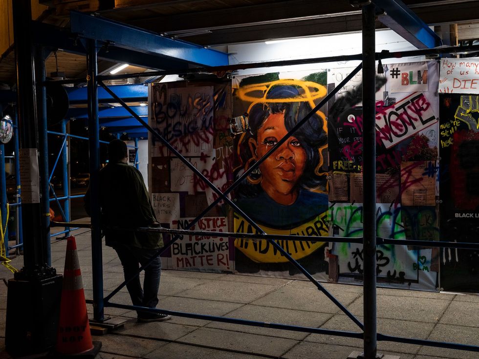 Op de avond vr de Commitment March naar Washington DC staat een voetganger stil voor een muurschildering van de 26jarige Breonna Taylor die in Louisville Kentucky door agenten werd doodgeschoten Haar dood leidde in de hele VS tot demonstraties