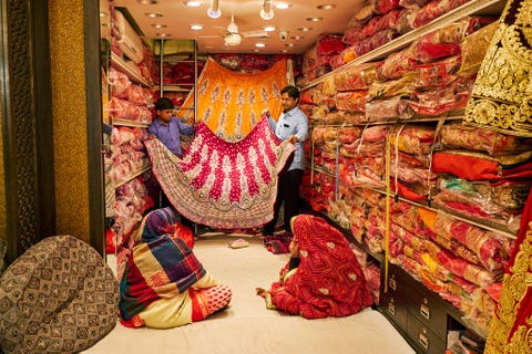 Vrouwen winkelen in een sariwinkel in Jaipur die van boven tot onder is gevuld met stoffen en kledingstukken Het zoeken van de juiste sari kan een urenlang odyssee zijn die het drinken van vele kopjeschaien het ter plekke laten vermaken van stoffen met zich meebrengt