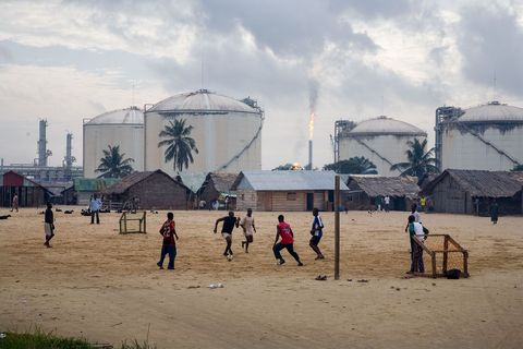 Voor een groep gastanks op Bonny Island in Nigeria spelen jongens een partijtje voetbal