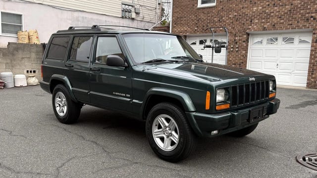 2001 Jeep Cherokee Limited 4x4 front three quarter view of a green jeep cherokee 4x4 with a boxy design, silver alloy wheels, and orange turn signals.