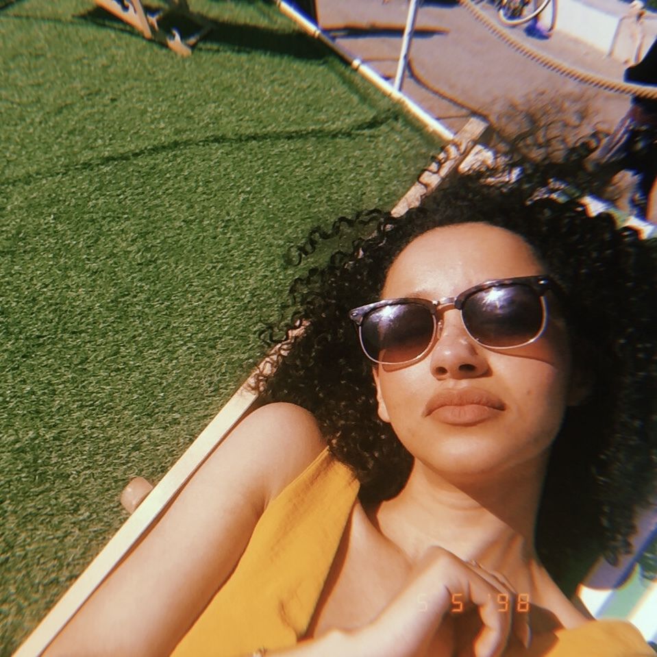 a woman with curly hair wearing sunglasses