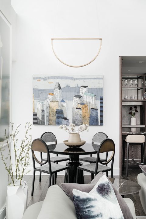 black dining table, grey couch, semi circle mirror, artwork of new york city
