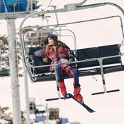 a model rides a chairlift at a ski resort wearing a moncler ski outfit to illustrate a roundup of apres ski style clothing 2022
