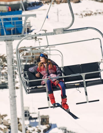 a model rides a chairlift at a ski resort wearing a moncler ski outfit to illustrate a roundup of apres ski style clothing 2023