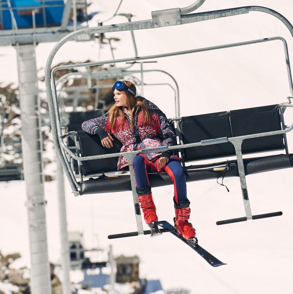 a model rides a chairlift at a ski resort wearing a moncler ski outfit to illustrate a roundup of apres ski style clothing 2023