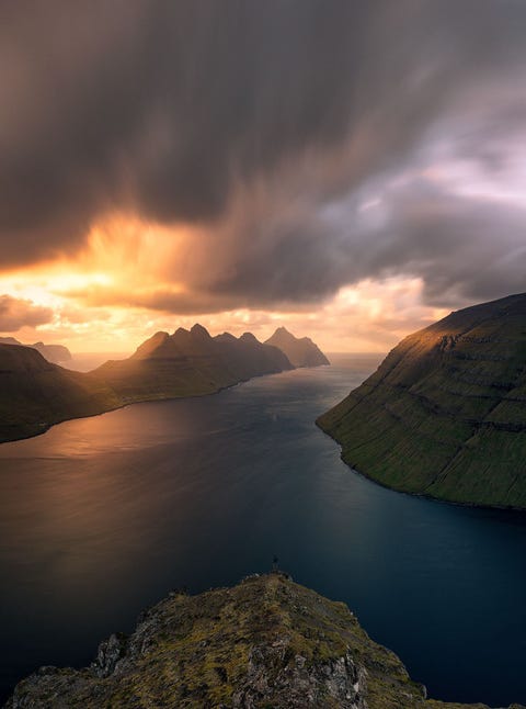 FAERÖER-EILANDEN FAEREREILANDENStel je voor dat je op een bergtop staat en je windvlagen vanuit het hoge noorden moet trotseren dat is een gewone dag op de Faerereilanden Deze foto werd tijdens het gouden uurtje gemaakt vanaf de berg Klakkur pal naast het plaatsje Klaksvik Vandaar heb je het prachtigste uitzicht over de omringende eilanden Het eiland Kalsoy is heel spectaculair omdat zijn vele bergen in het licht van de ondergaande zon baden