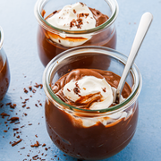 chocolate pudding in glass jars with whipped cream and chocolate shavings