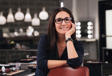 bobbi brown standing in a makeup studio smiling looking at the camera wearing glasses