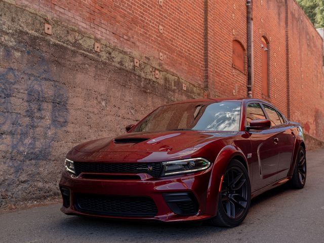 2023 red dodge charger scat pack widebody parked in an alleyway downhill