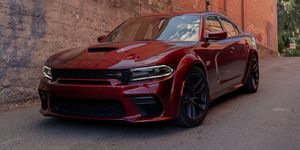 2023 red dodge charger scat pack widebody parked in an alleyway downhill