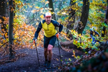 man in geel shirt op berg aan het trailrunnen in het bos