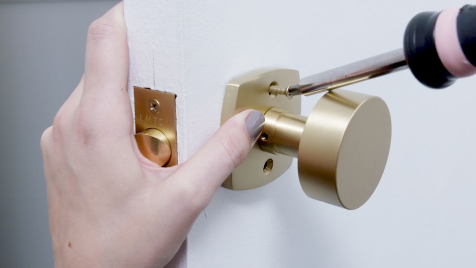 person unscrewing door knob