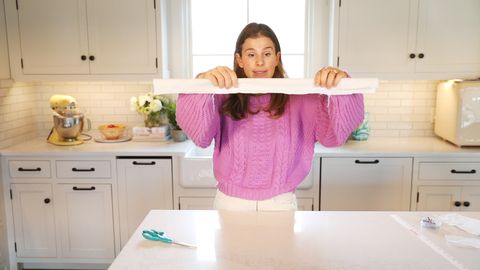 woman in pink sweater holding fabric strip