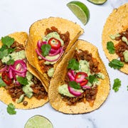 vegan tacos made with lentils in flour tortillas with pickled onions, green sauce, and cilantro