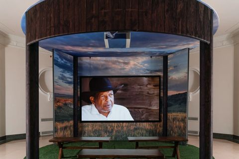 museum exhibit with black cowboy on screen
