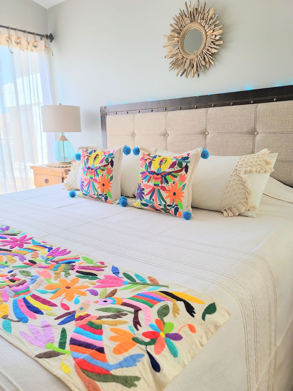 a bedroom designed by soluna paz features otomi embroidery on a blanket and a pair of pillows