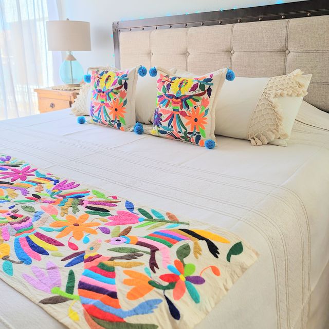 a bedroom designed by soluna paz features otomi embroidery on a blanket and a pair of pillows