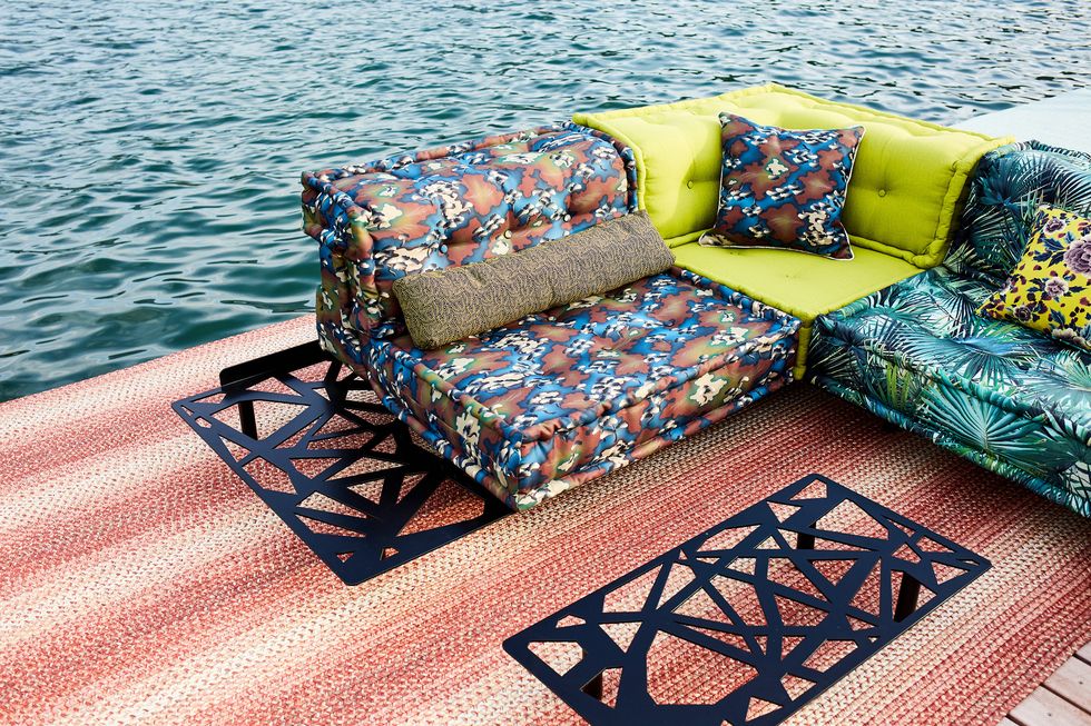 a closeup of a modular sofa by the water with brown, neon green and turquoise patterned cushions