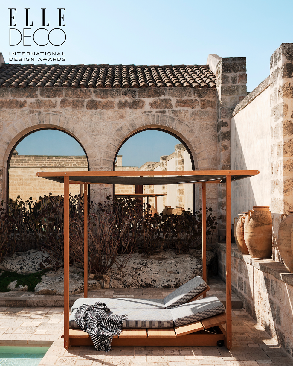 Outdoor lounge area with a wooden daybed and decorative pottery. Outdoor lounge area with a wooden daybed and decorative pottery.