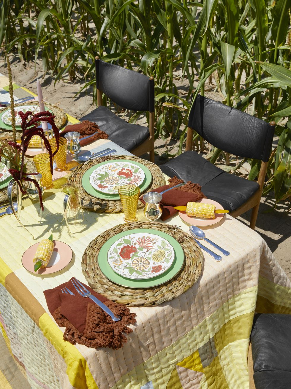 an outdoor table setting with bright yellow colors and corn on the cob