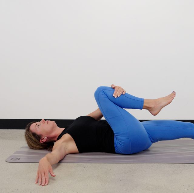 woman laying on yoga mat while stretching right leg