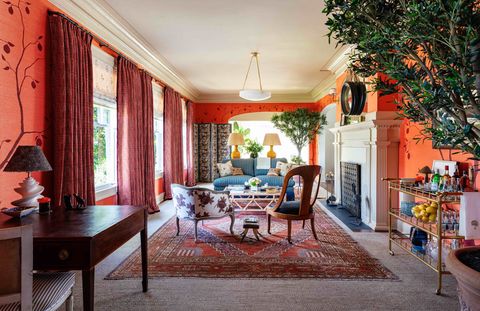a large sitting room with red walls a small seating area and a fireplace