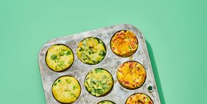 a metal muffin pan of twelve baked egg muffins, on a green background