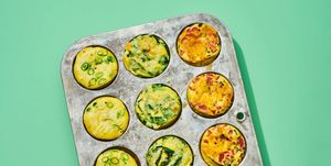 a metal muffin pan of twelve baked egg muffins, on a green background