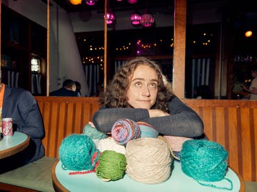 a person sitting at a table with yarn