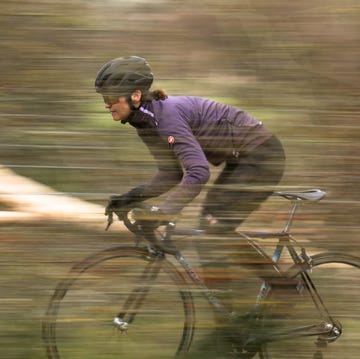 een vrouw op een racefiets met paars fietsjack aan