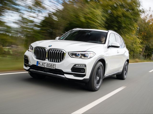 2023 white bmw x5 suv driving along tree lined road