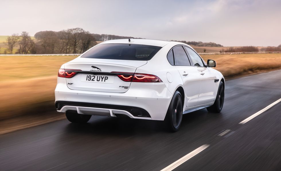2023 white jaguar xf sedan driving an empty country road at sunset