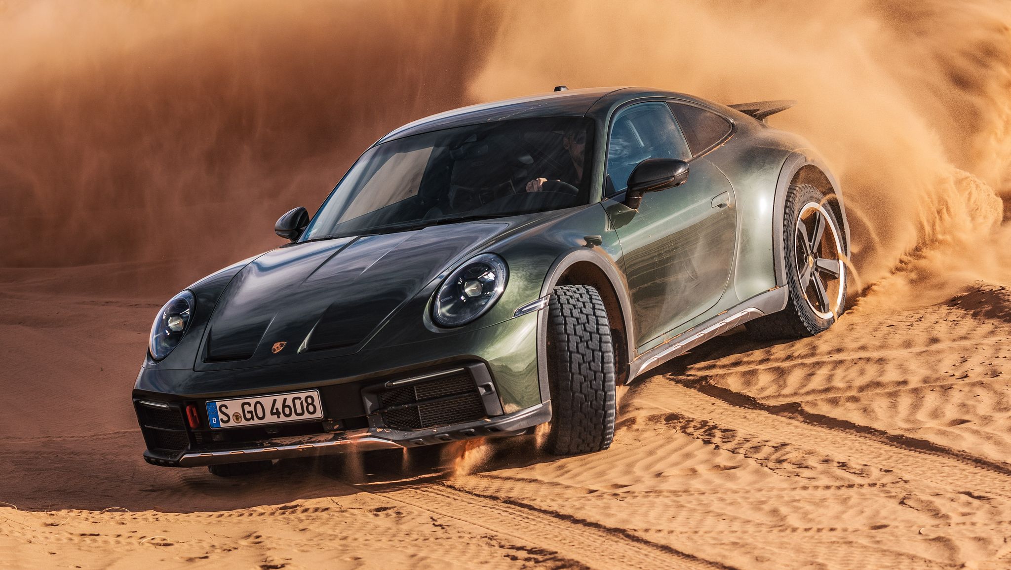 2024 Dark green Porsche 911 Dakar drifting in a sand dune